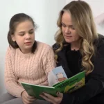 En flicka läser en bok med en vuxen kvinna.