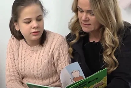 En flicka läser en bok med en vuxen kvinna.