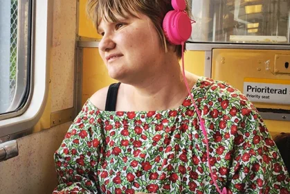 Kvinna med rosa hörlurar som åker tunnelbana.