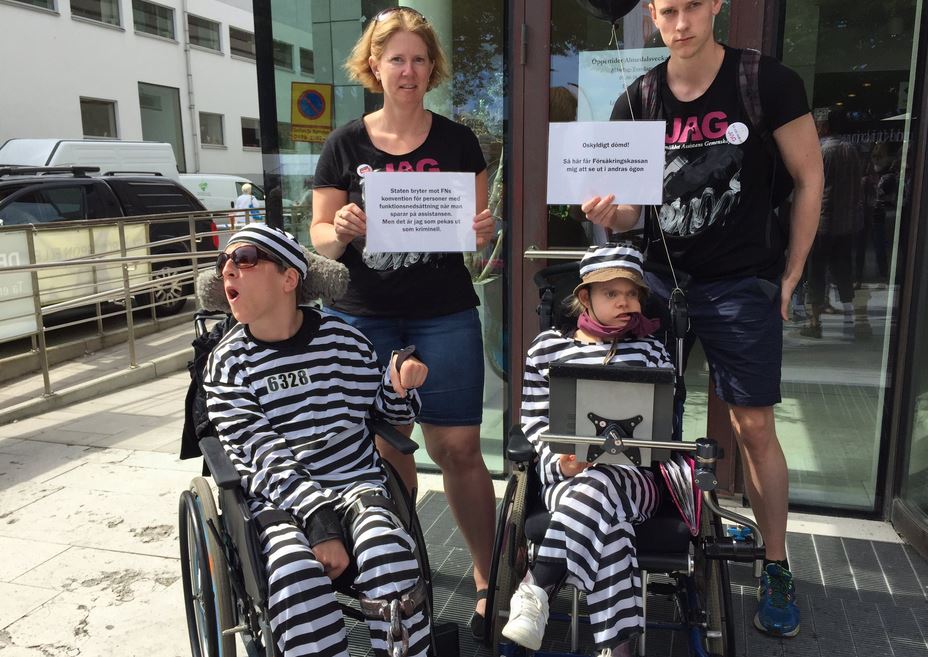 Två rullstolsburna personer klädda i randiga fångdräkter.