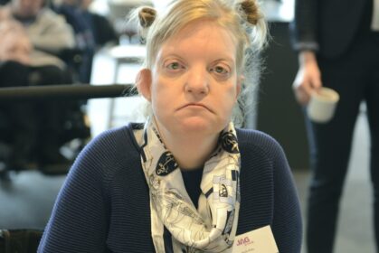 Ung kvinna med blont uppsatt hår som tittar allvarligt in i kameran